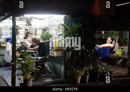 Eine Familie von Friseuren arbeitet in der Nacht, ein Leben auf der Straße-Szene in Bangkok in den Tagen nach dem Tod von König Rama IX. Stockfoto