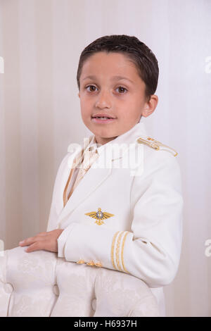 Junge mit schweren Ausdruck stehen und blickte in die Kamera in seine erste Heilige Kommunion. Stockfoto