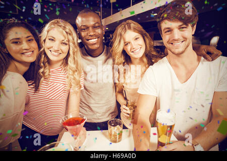 Zusammengesetztes Bild Porträt der happy Friends mit Bier und Cocktails auf Tisch Stockfoto