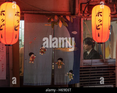 Chochin Laternen und Noren (暖簾) außerhalb Restaurant Bar Izakaya mit männlicher Kunde Gehalt Mann in Anzug, Takadanobaba Tokio Nacht Stockfoto