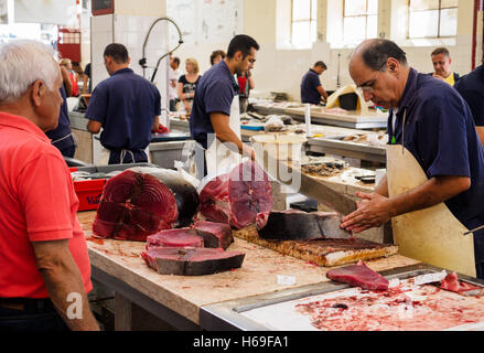 Ein Fischhändler schneidet Scheiben Thunfisch mit einer Machete Messer in der Markthalle von Funchal auf der portugiesischen Insel Madeira Stockfoto