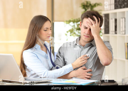 Arzt untersucht einen Patienten auskultieren mit einem Stethoskop in der Innenansicht Büro Stockfoto