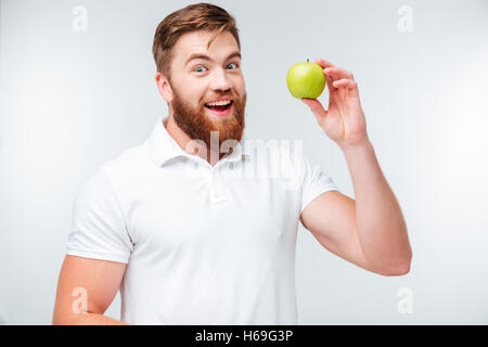 Glücklicher bärtigen Mann hält grünen Apfel und Blick in die Kamera, die isoliert auf weißem Hintergrund Stockfoto