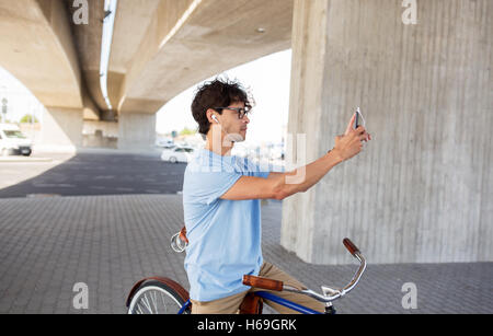 Mann mit Smartphone und Ohrhörer auf dem Fahrrad Stockfoto