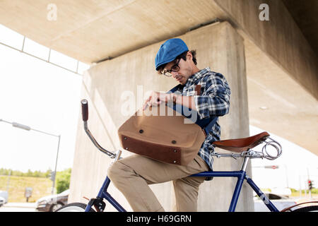 Hipster-Mann mit Fahrrad auf der Suche etwas in der Tasche Stockfoto