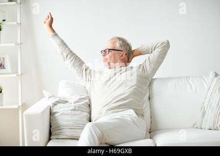 Senior woman in Gläsern entspannend auf sofa Stockfoto