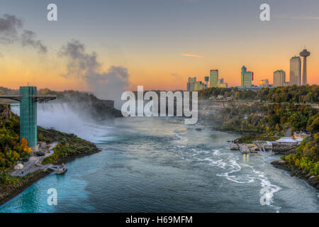 Der Niagara River, darunter die American Falls, die Horseshoe Falls und die Skyline von Niagara Falls, Ontario kurz vor Sonnenaufgang. Stockfoto