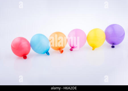 Bunte kleine Luftballons in Linie auf weißem Hintergrund Stockfoto