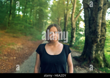 Schöne junge Erwachsene weibliche Blick in die Kamera im Wald, Wandern Frau mit Rucksack posiert im Park oder Wald Stockfoto