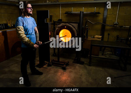 Spezialist für Glasbläser James Devereux heizt eine weiche Scheibe aus geschmolzenem Glas, wie er klar Glas Rondelle für eine Skulptur in seiner Werkstatt in Wiltshire. Stockfoto