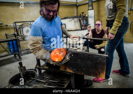 Spezialist für Glasbläser James Devereux verwendet nasse Zeitung, um eine Stück aus geschmolzenem Glas zu gestalten, wie er klar Glas Rondelle für eine Skulptur in seiner Werkstatt in Wiltshire. Stockfoto