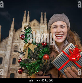 Lustige Weihnachten Reise nach Mailand, Italien. Porträt der fröhliche moderne Frau mit Weihnachtsbaum und Geschenk in Mailand, Italien Stockfoto