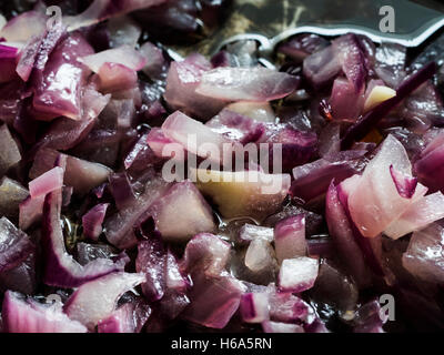 Nahaufnahme von roten Zwiebeln in Öl in einer Pfanne braten Stockfoto