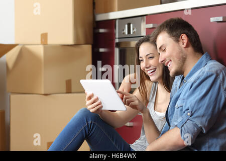 Paar Wohnortwechsel und mit einer Tablette, die sitzen auf dem Boden in der Küche online kaufen Stockfoto