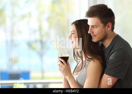 Seite Ansicht Porträt einer nachdenklichen paar oder Ehe umarmt und im freien Blick durch ein Fenster eines Hotelzimmers Stockfoto