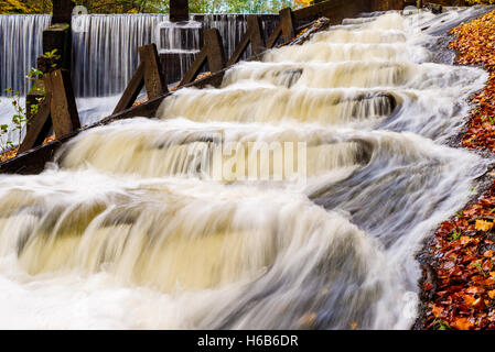 Fischtreppe mit Stromschnellen im Herbst. Wasser fließt in Schritten ist hilfreich für die Migration Fisch, den Damm in die Hinterg sichtbar zu überwinden Stockfoto