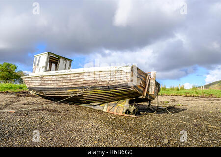 Sonne scheint auf die abblätternde Farbe der freiliegenden Unterseite der eine verlassene hölzerne Boot Wrack am Ufer des Loch Harport auf Insel Stockfoto