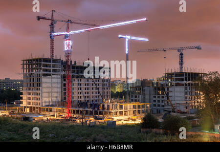 Viele Turmdrehkrane bauen Wohngebäude am Abend Stockfoto