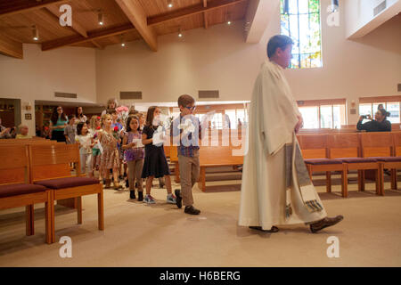 Ein Priester in der Kirche St. Timothy, Laguna Niguel, CA, führt eine Prozession von Kindern zur feierlichen Krönung Mariens. Das Ereignis bezieht sich auf spezielle Marienandachten gehalten in der katholischen Kirche im Laufe des Monats Mai zu Ehren der Jungfrau Maria als ' th Stockfoto