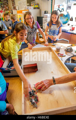 Begeisterte multirassische Grundschüler in Mission Viejo, Kalifornien, zeigen Klasse-Projekt Roboter auf einer Tischplatte. Stockfoto