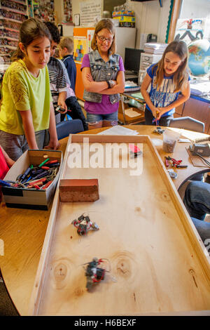 Begeisterte multirassische Grundschüler in Mission Viejo, Kalifornien, zeigen Klasse-Projekt Roboter auf einer Tischplatte. Stockfoto