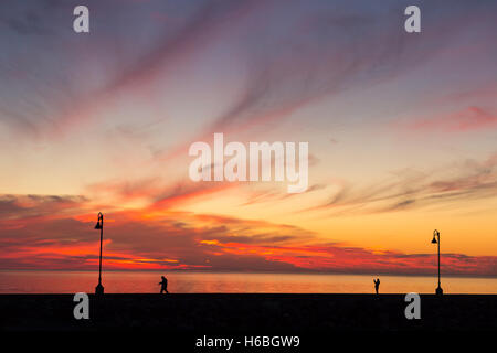 Sonnenuntergang in Sainte-Flavie, Quebec, Kanada, mit Silhouetten von Menschen zu Fuß auf dem Steg Stockfoto