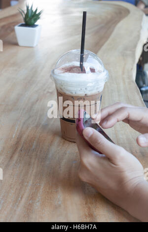 Frau Hand mit Telefon mit Hintergrund der Eiskaffee, Fotoarchiv Stockfoto