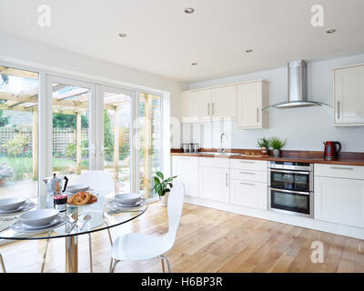 Eine moderne, frische offene Küche mit integriertem Backofen, Arbeitsplatten Herd, Dunstabzugshaube & Holz. Oxfordshire, Vereinigtes Königreich Stockfoto