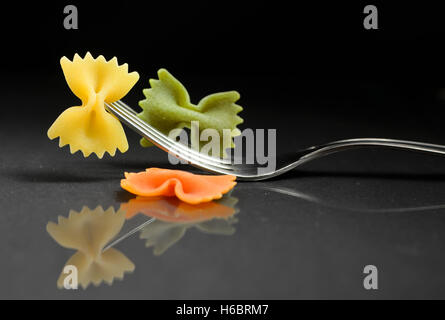 Pasta Farfalle auf einer Gabel auf schwarzem Hintergrund Stockfoto