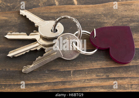 Schlüssel und Herz Schlüsselanhänger auf einem rustikalen hölzernen Hintergrund. Stockfoto