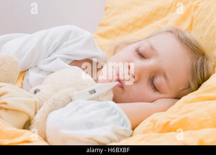 Krankes Mädchen mit Fieberthermometer im Bett Stockfoto