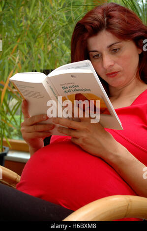 Schwangere Frau liest Buch über Babys Stockfoto