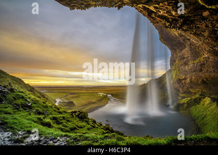 Sommer Sonnenuntergang über den berühmten Wasserfall Seljalandsfoss in Island gesehen hinter dem Sturz. Stockfoto