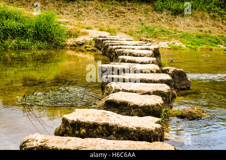 Trittsteine überqueren einen kleinen Fluss im Sommer Stockfoto