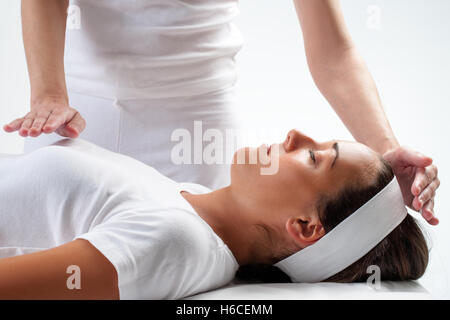 Nahaufnahme von Chiropraktoren Hände Reiki auf junge Frau zu tun. Einerseits auf Kopf und eine hand auf die Brust. Stockfoto