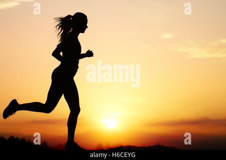 Aktion Silhouette des weiblichen Jogger bei Sonnenuntergang hautnah. Mädchen wieder gegen intensiven orangefarbenen Himmel beleuchtet. Stockfoto