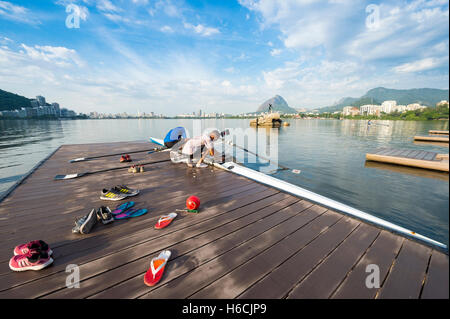 RIO DE JANEIRO - 14. März 2016: Schuhe liegt im Vordergrund, wie eine brasilianische Ruderer sein Boot auf Lagoa bereitet. Stockfoto