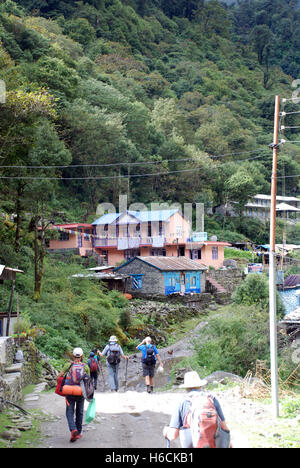 Wanderer auf dem Annapurna Circuit in Nepal gehen in Richtung eines kleinen Dorfes Stockfoto