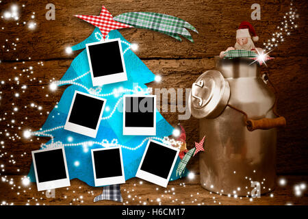 Sechs leere Bilderrahmen hängen an einem Weihnachtsbaum und lustige Weihnachtsmann in einem alten Topf mit Milch auf hölzernen Hintergrund Stockfoto