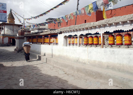 eine Frau geht vorbei an Gebetsmühlen in der Mustang Hauptstadt Lo Manthang in Nepal Stockfoto