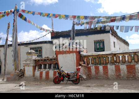 Ein Motor cycle Vor buddhistischen Gebetsmühlen in der Stadt Lo Manthang in Nepal geparkt Stockfoto