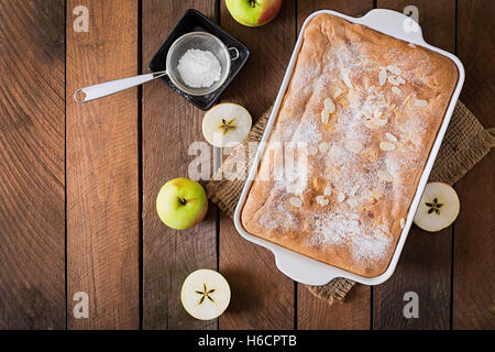 Apfelkuchen "Charlotte" mit Mandel Blütenblättern und Puderzucker. Ansicht von oben Stockfoto