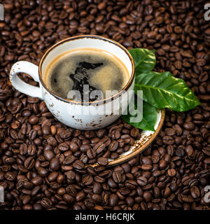 Schwarzer Kaffee mit grünen Blätter auf Caffee Bohnen Hintergrund. Vintage-Stil getönten Bild Stockfoto