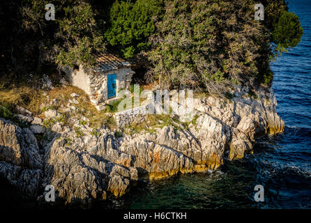 Kleine alte steinerne Lodge auf einem felsigen Ufer Stockfoto