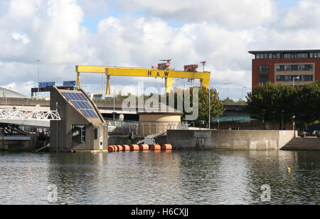 Der Lagan Weir auf dem Fluss Lagan mit Harland & Wolff Krane im Hintergrund. Stockfoto