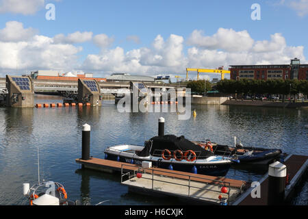 Der Lagan Weir auf dem Fluss Lagan mit Harland & Wolff Krane im Hintergrund. Stockfoto