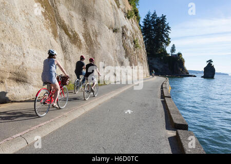 Vancouver, Kanada: Gruppe von Radfahrern entlang Stanley Park Seawall Schleife fahren. In der Ferne ist Wahrzeichen Siwash Rock. Stockfoto