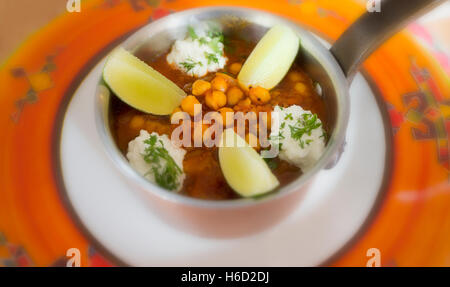 Kichererbsen Curry mit Kurkuma und Tomaten mit Kalk und Joghurt serviert in einem Kupfer pan Stockfoto