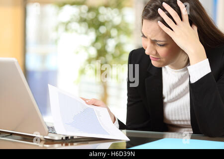 Besorgt Geschäftsfrau in Konkurs gerade verringerte Verkaufsstatistiken in ein Dokument in Papierform im Büro Stockfoto