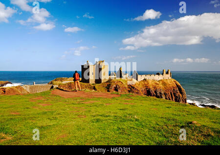 Ein Blick auf einen Wanderer, der die Ruinen von Dunnottar Castle in der Nähe von Stonehaven, Aberdeenshire, Schottland, Großbritannien bewundert. Stockfoto